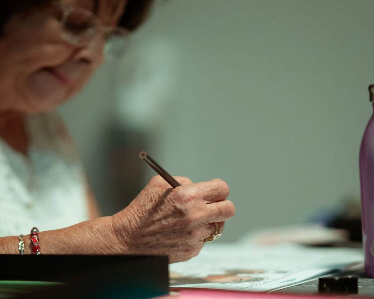 Starija žena zapisuje informacije na papir tokom edukativne aktivnosti.